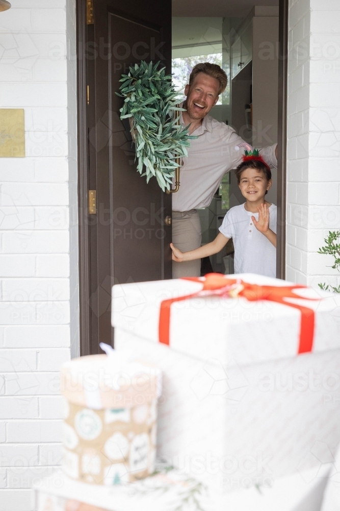 Father and son opening door with presents outside - Australian Stock Image