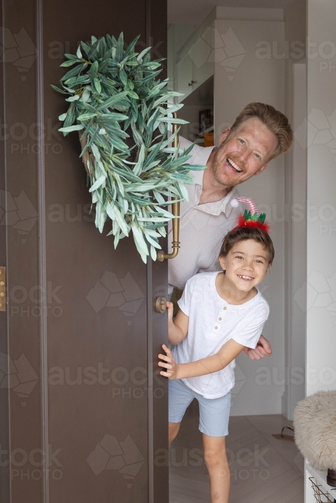 Father and son opening door with wreath together - Australian Stock Image