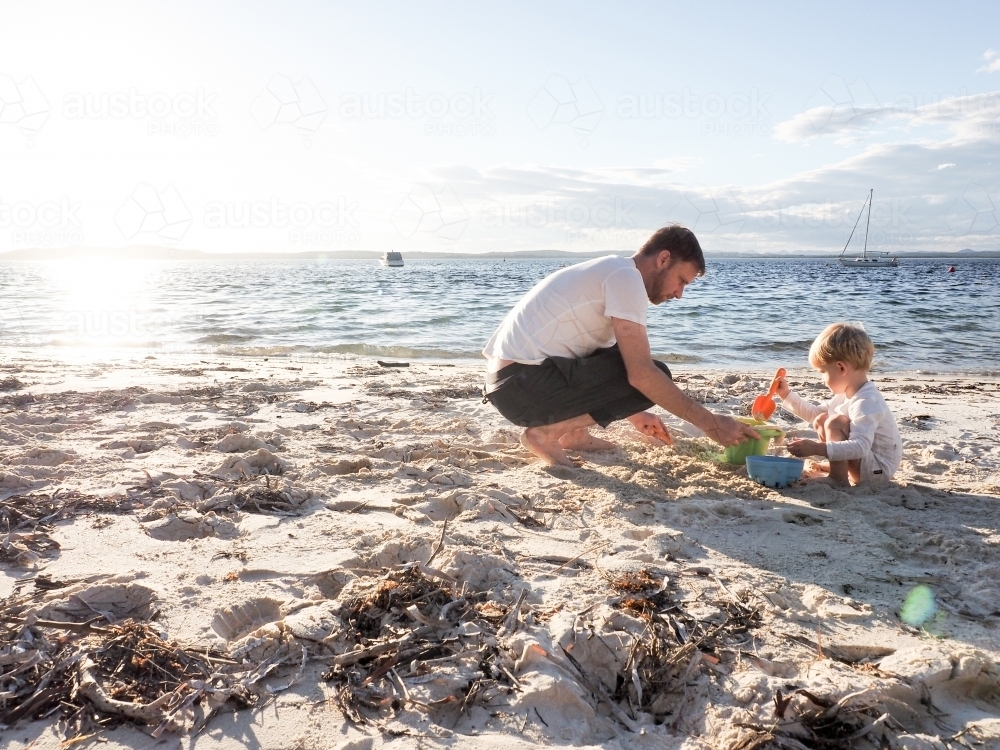 Father and son playing at the beach at sunset - Australian Stock Image