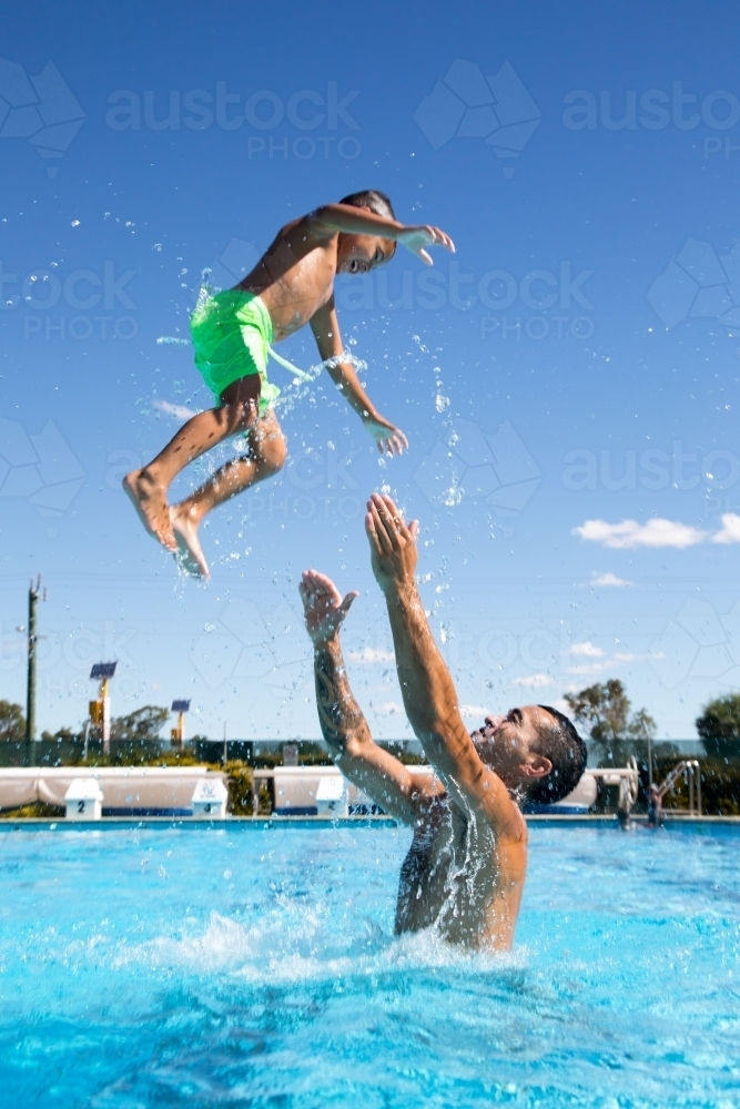 Father and son playing in swimming pool - Australian Stock Image