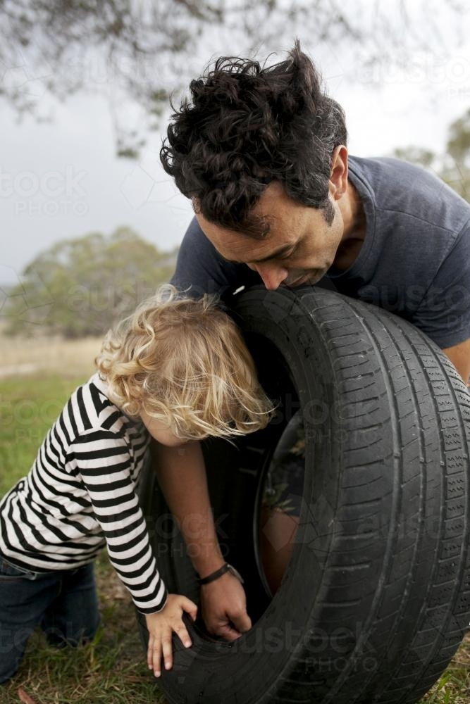 Father and son putting together a tyre swing in country backyard - Australian Stock Image