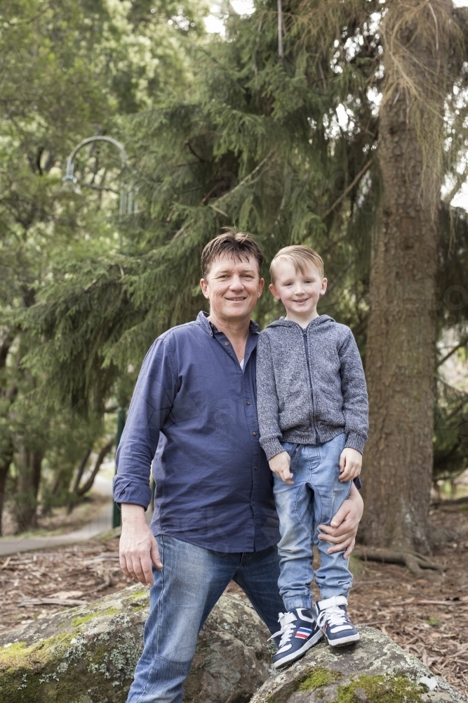 Father and son standing on rocks, smiling for camera - Australian Stock Image