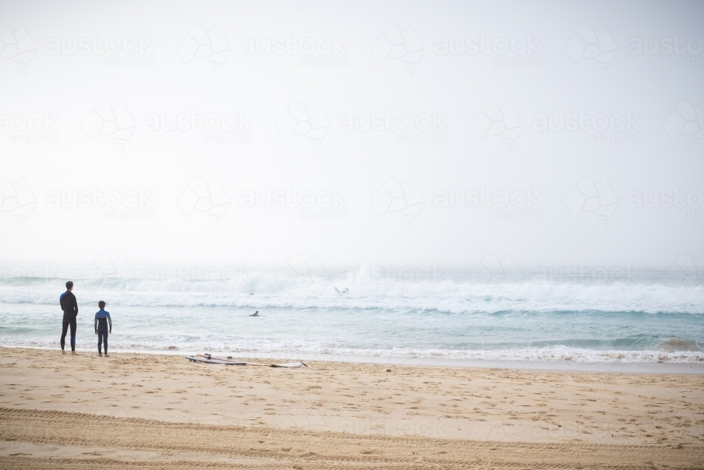 father and son surfers enjoy the waves and dense fog - Australian Stock Image
