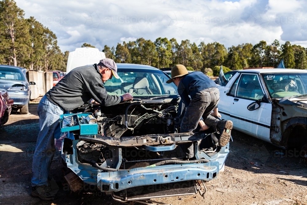 Father and son working a wreckers pulling apart old car for parts - Australian Stock Image
