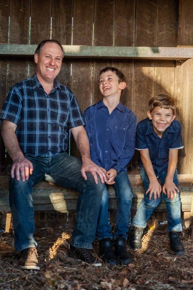 Father and sons sitting together in rural country setting - Australian Stock Image