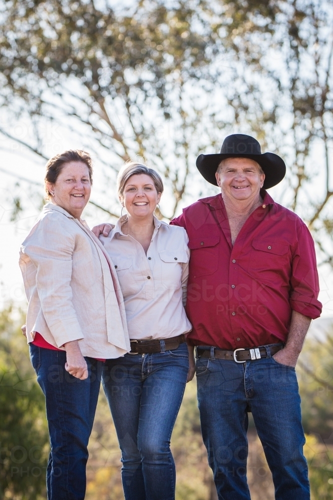 Father and step mother standing smiling with daughter on family farm in drought - Australian Stock Image