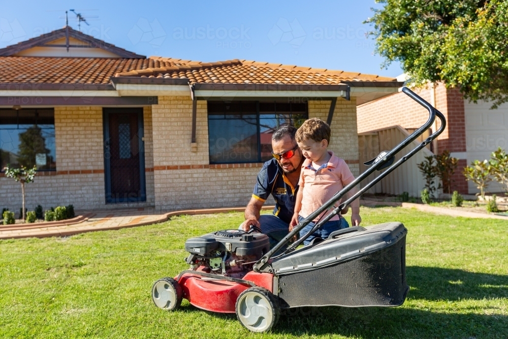 father and toddler with lawnmower - Australian Stock Image