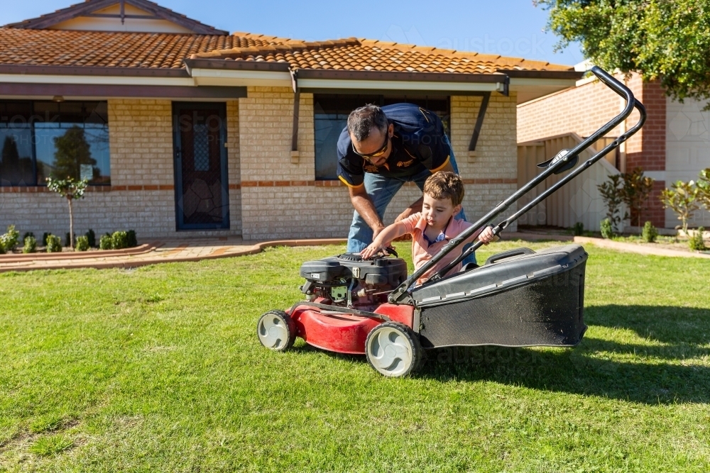 father and toddler with lawnmower - Australian Stock Image