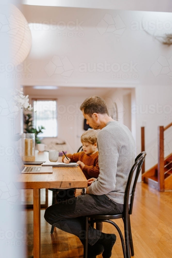 Image of Father and young son doing homework together at table ...