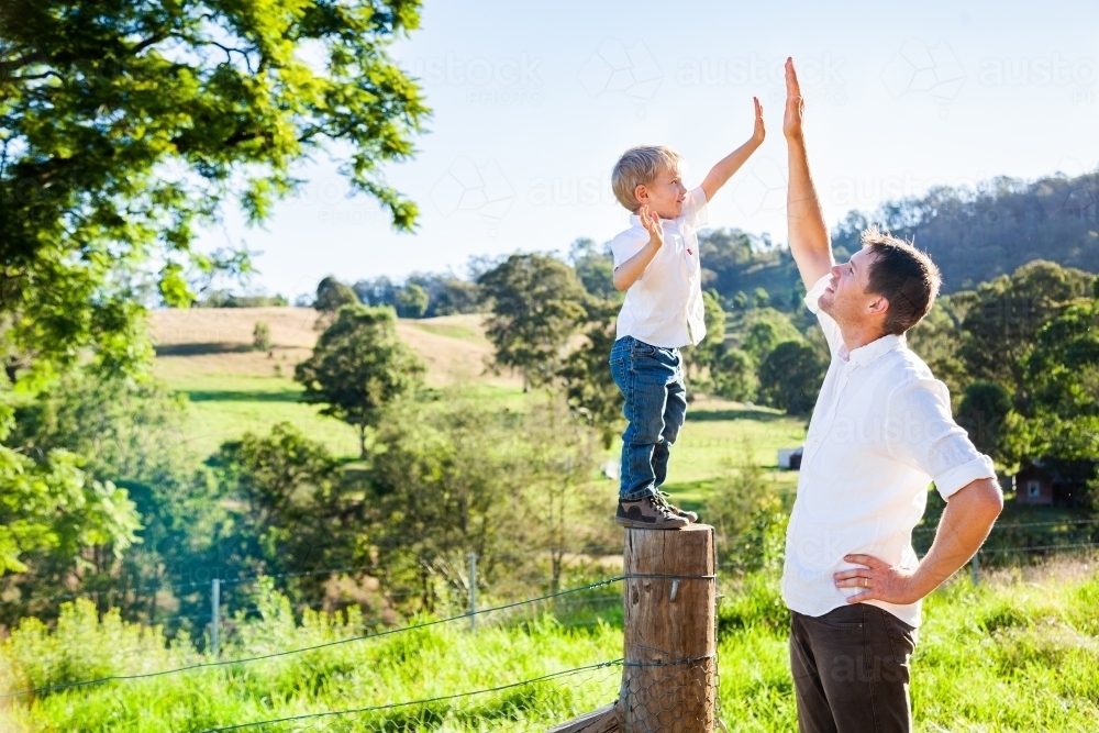 Father and young son high five hands outside - Australian Stock Image