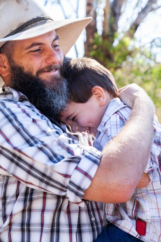 Father and young son hugging outside - Australian Stock Image