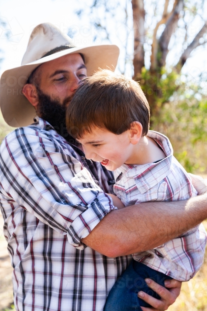 Father and young son hugging outside - Australian Stock Image