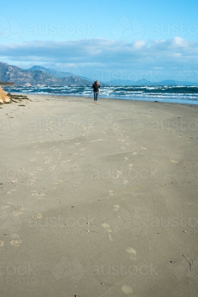 Father carrying son on his back along beach - Australian Stock Image