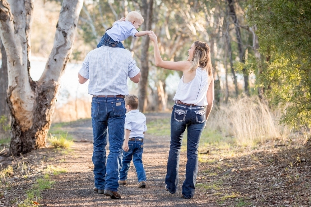 Father carrying young boy on shoulders with mother holding his hand - Australian Stock Image