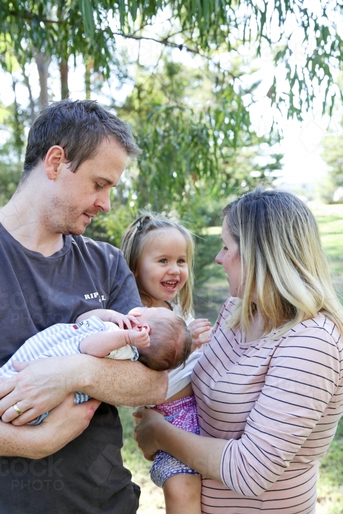 Father cradling new baby with mother and sister - Australian Stock Image