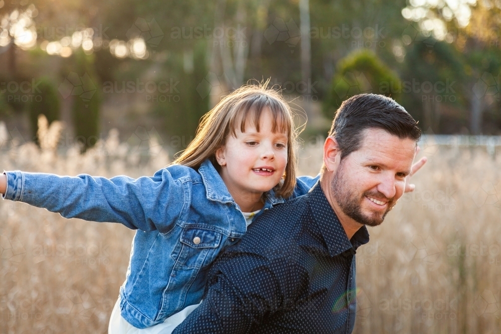 Father giving daughter a piggy back ride - Australian Stock Image