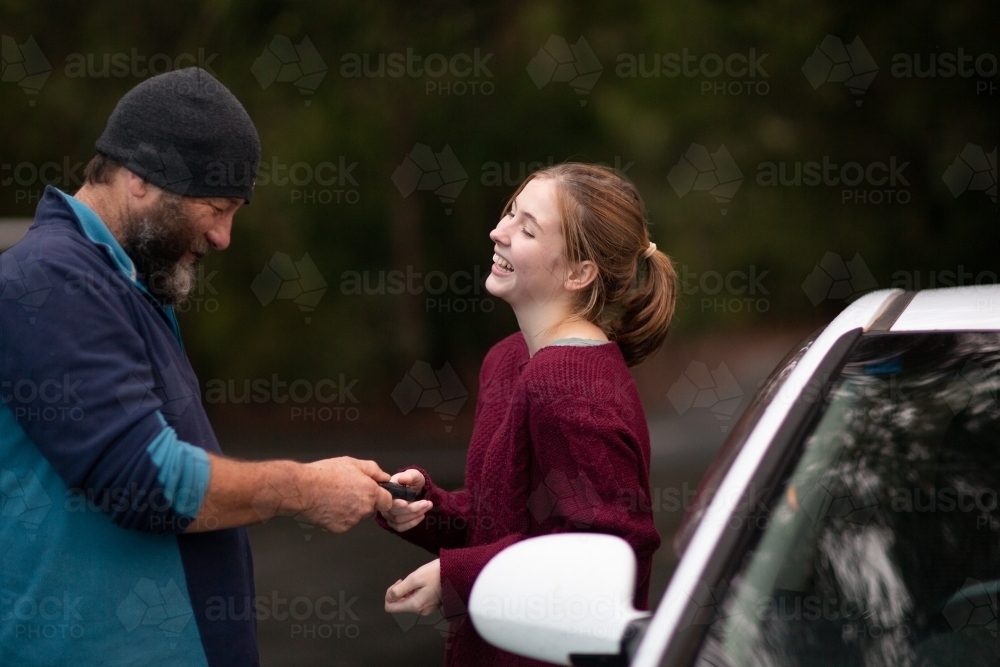 Father handing car keys to teenaged daughter - Australian Stock Image