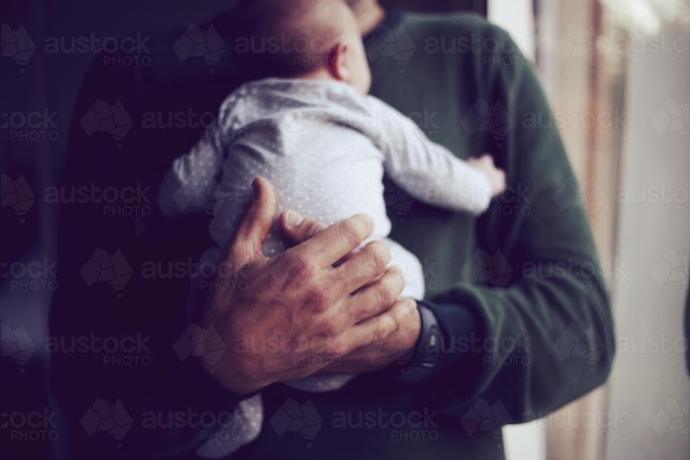 Father holding baby on chest - Australian Stock Image