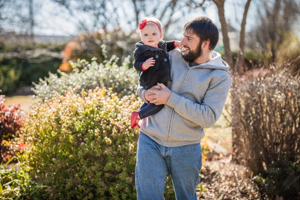 Father holding daughter on hip looking and smiling - Australian Stock Image