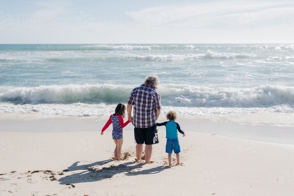 Father holding his children's hands at the beach, Victoria, Australia - Australian Stock Image