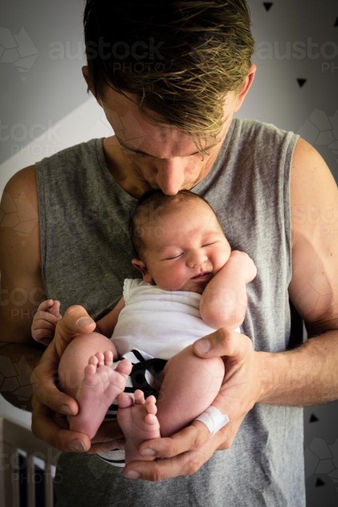 Father holding newborn baby and kissing head - Australian Stock Image