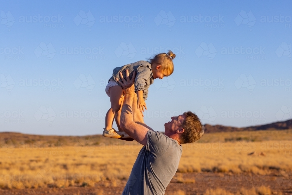 father holding toddler up in the air - Australian Stock Image