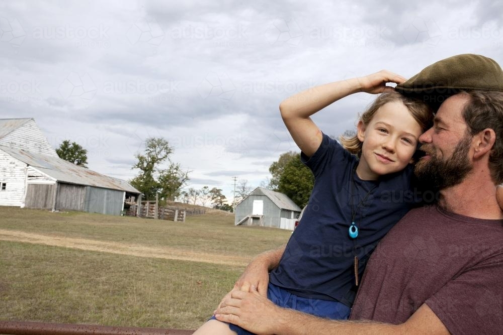 Father hugging daughter with farm sheds in background - Australian Stock Image
