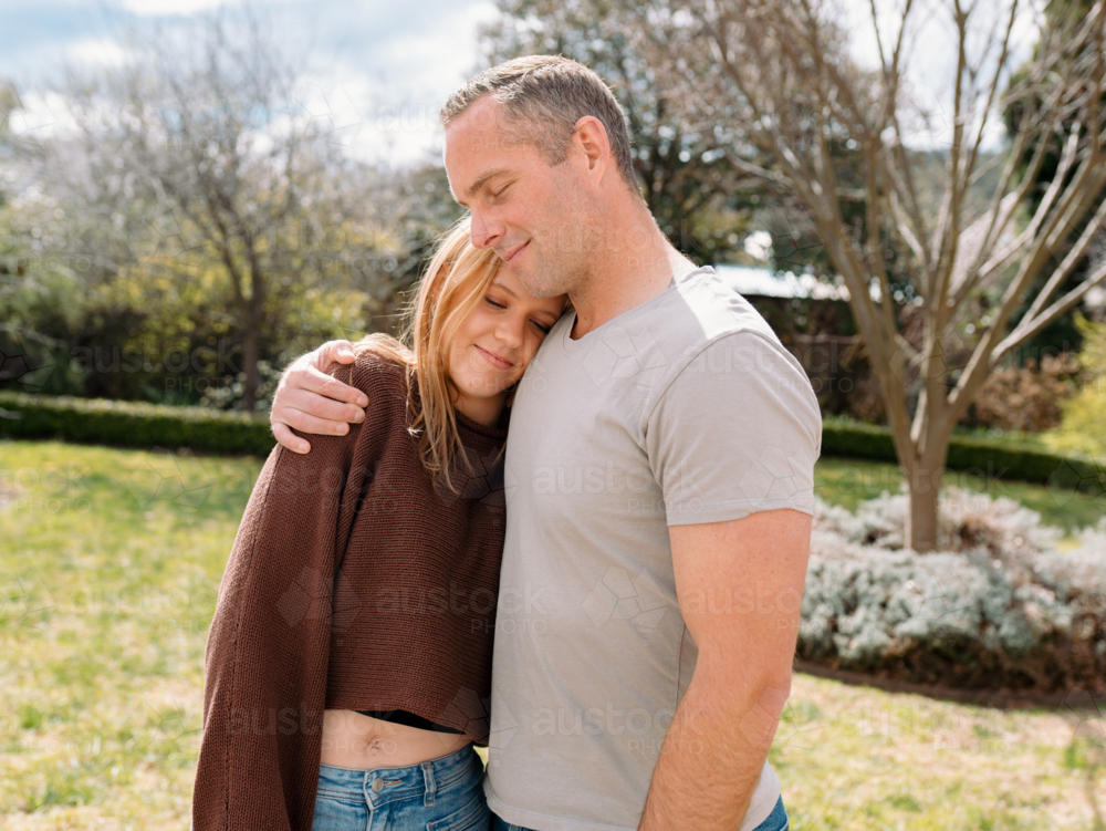 Father hugging teenage daughter in the garden - Australian Stock Image