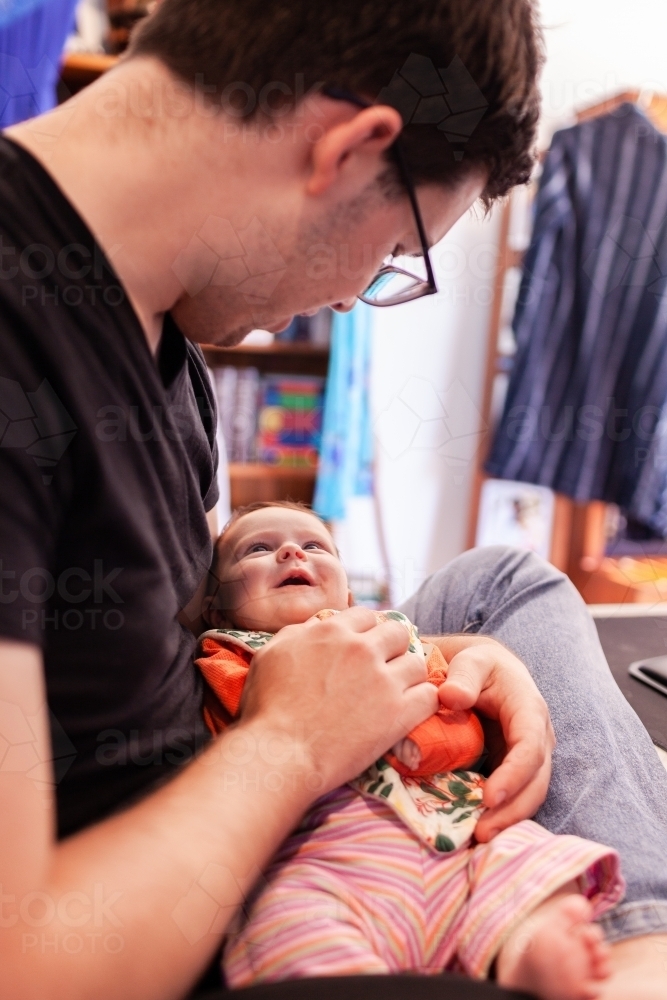 Father interacting with baby daughter smiling up at him - Australian Stock Image