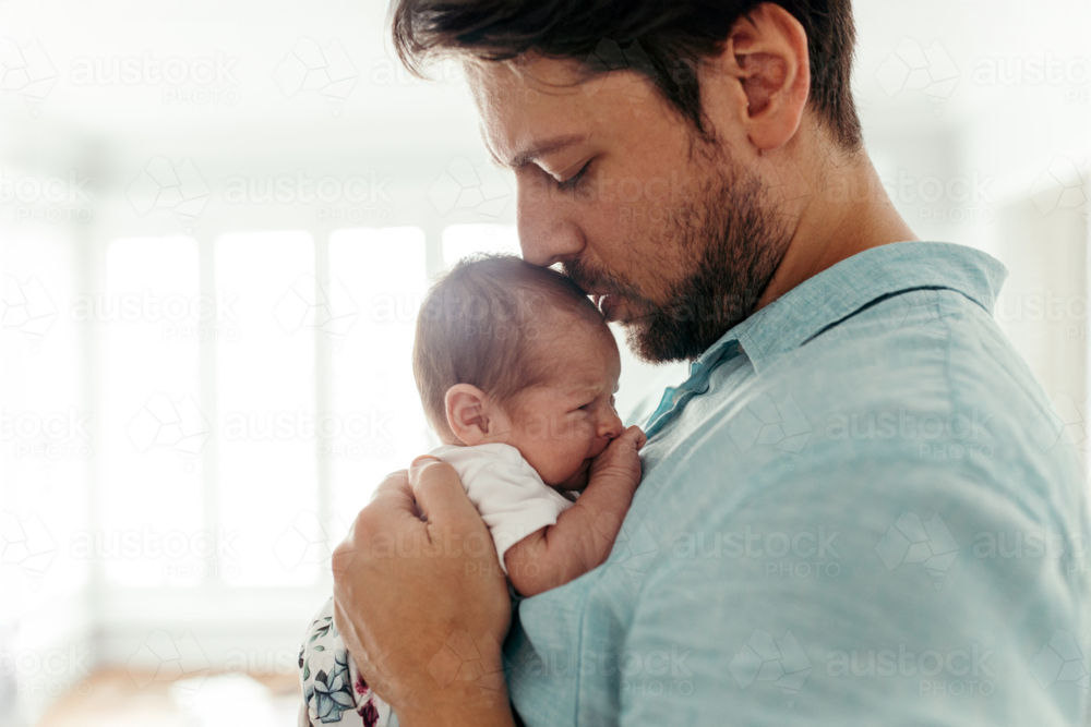 Father kissing newborn baby girls forehead - Australian Stock Image