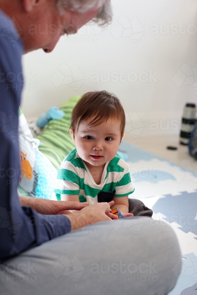 Father playing with baby boy in living room - Australian Stock Image