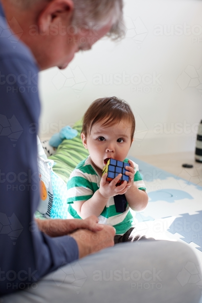Father playing with baby boy in living room - Australian Stock Image