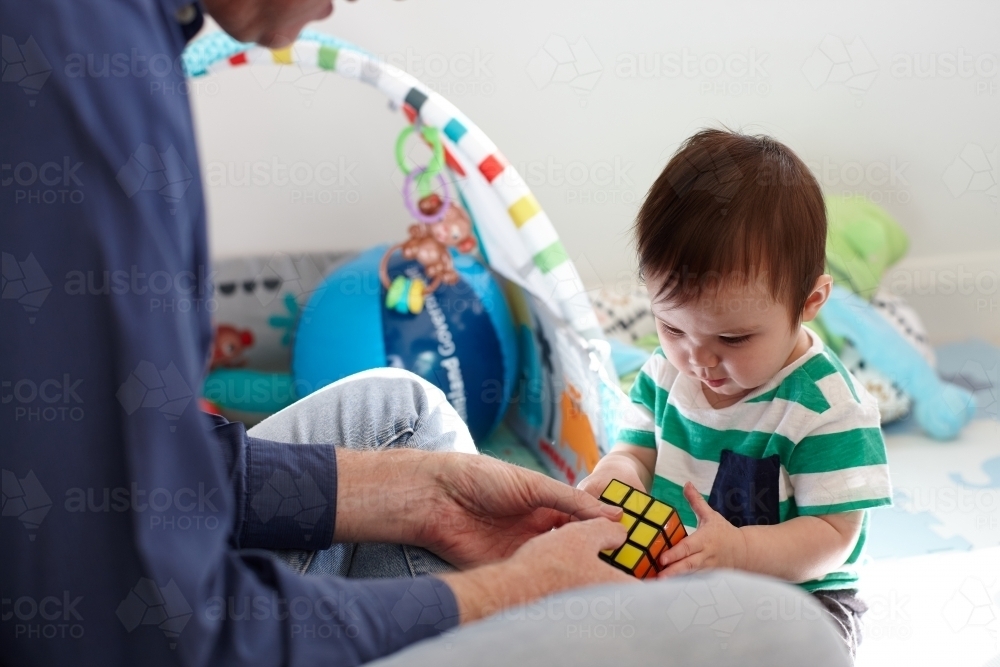 Father playing with baby boy in living room - Australian Stock Image