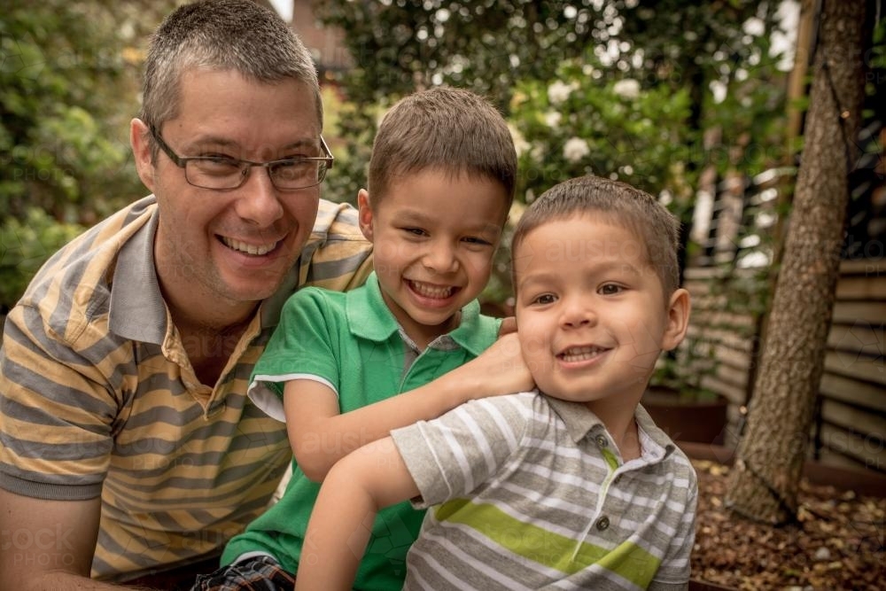 Father plays with his boys outside in an urban backyard - Australian Stock Image