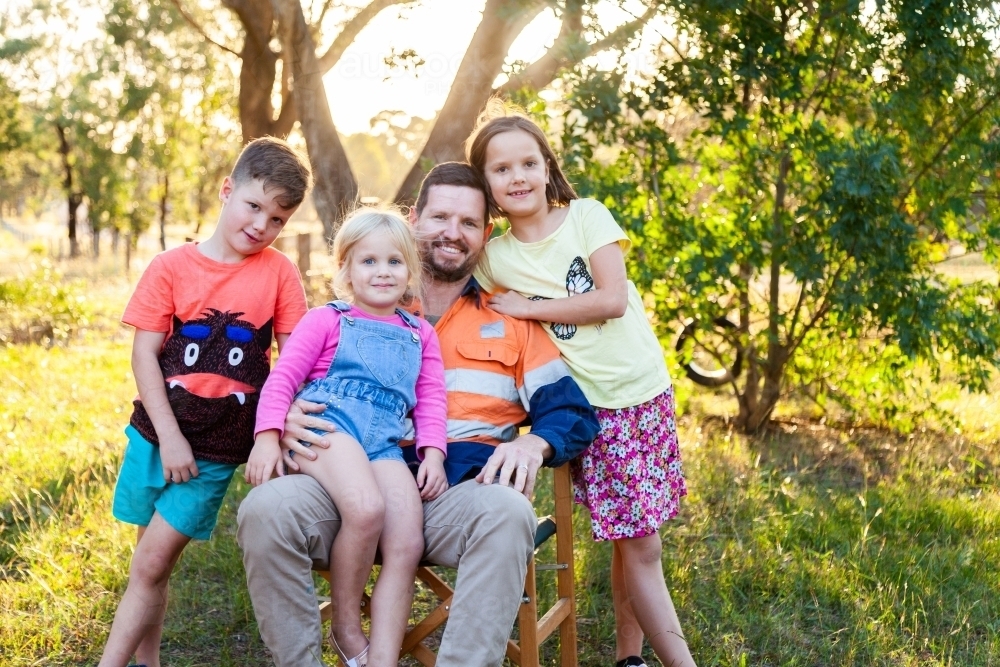 Father relaxing with three of his kids outside - Australian Stock Image