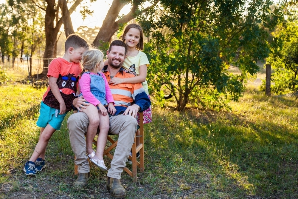 Father relaxing with three of his kids outside - Australian Stock Image