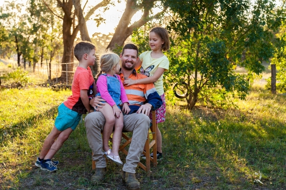 Father relaxing with three of his kids outside - Australian Stock Image