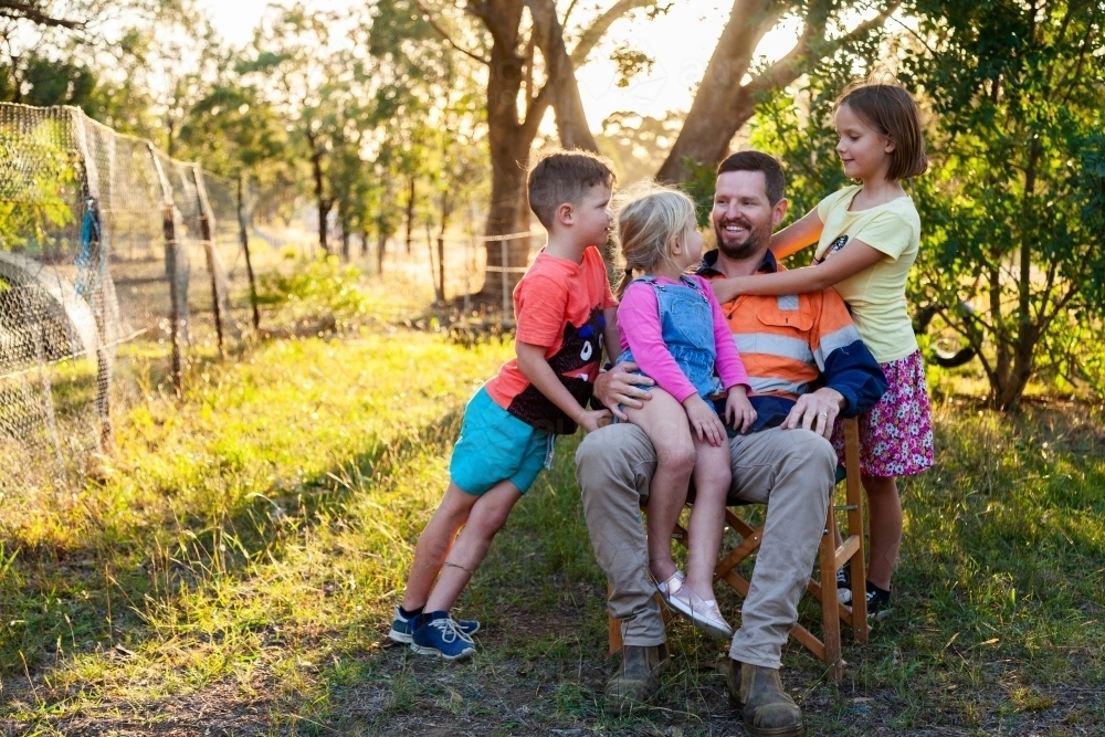 Father relaxing with three of his kids outside - Australian Stock Image