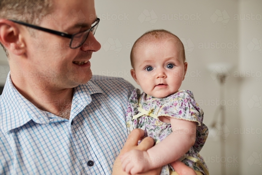 Father smiling lovingly at his baby daughter - Australian Stock Image