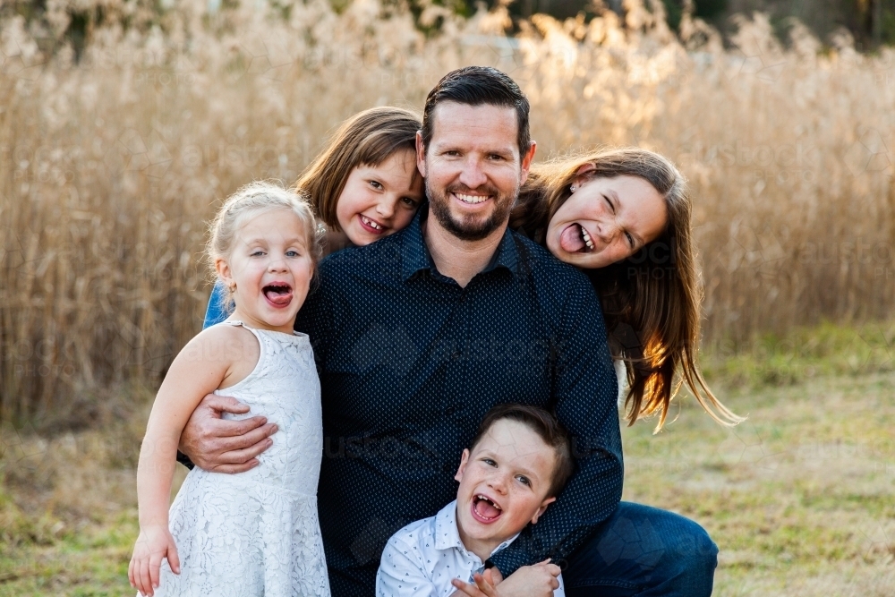 Father smiling of portrait with his four happy children - Australian Stock Image