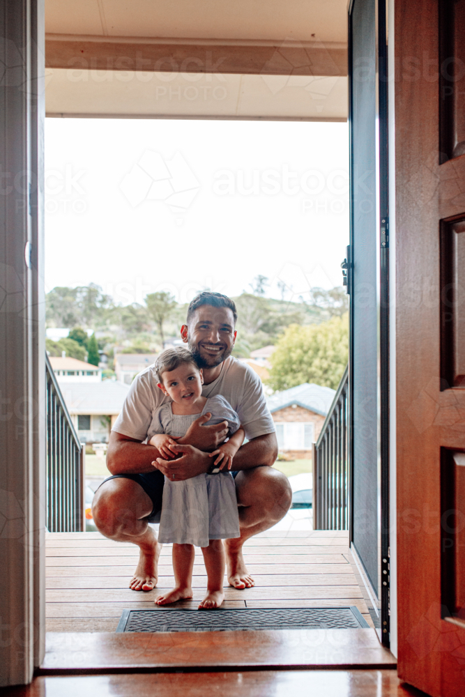 Father squatting holding toddler daughter on the doorway. - Australian Stock Image