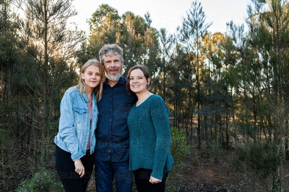 Father standing with happy daughters outside in bushland - Australian Stock Image