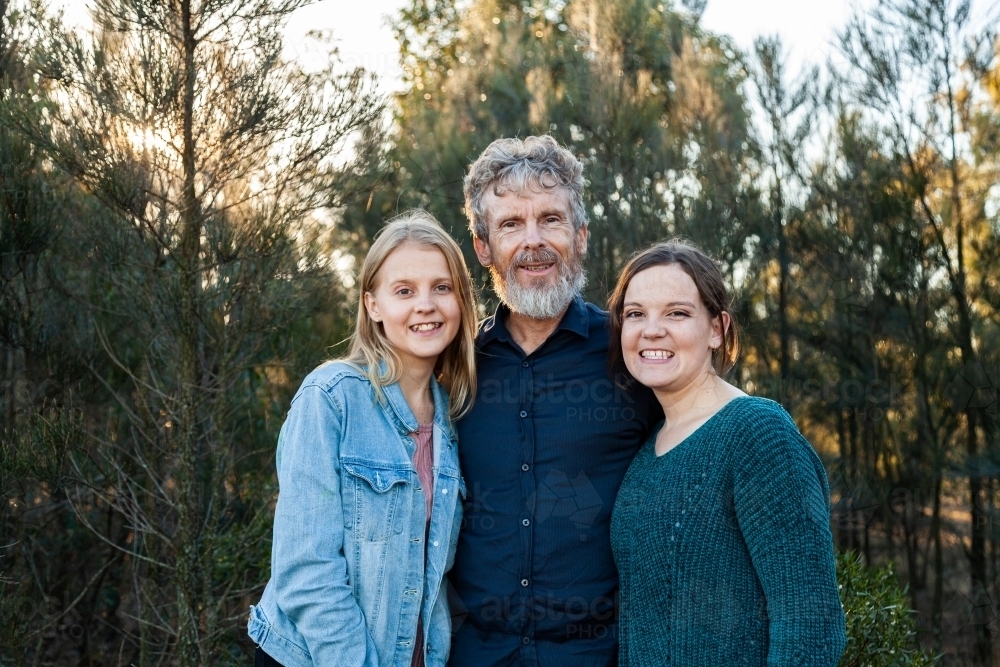 Father standing with happy daughters outside in bushland - Australian Stock Image