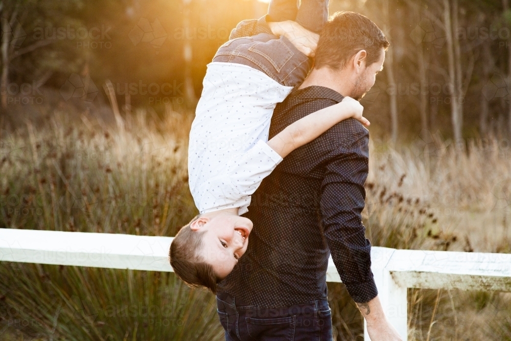Image of Father tipping son over his shoulder to carry him - Austockphoto