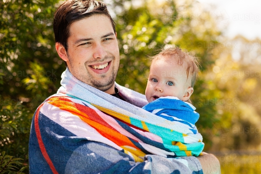 Image of Father with baby wrapped up in towel after swimming in pool in