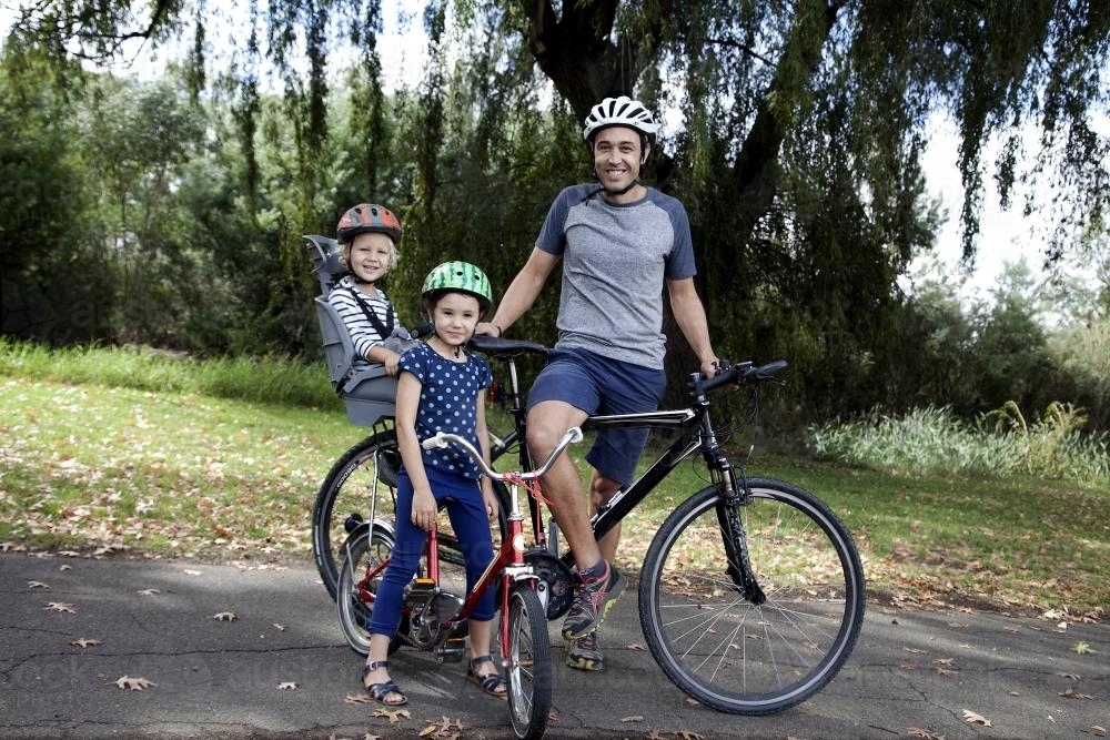 Father with two kids on a family bike ride - Australian Stock Image