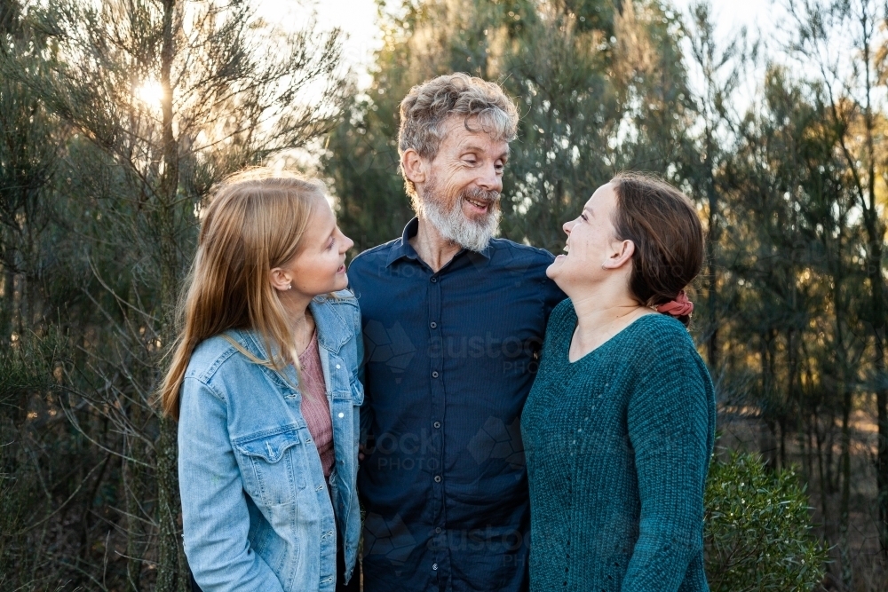 Father with young adult daughters smiling together in bushland - Australian Stock Image