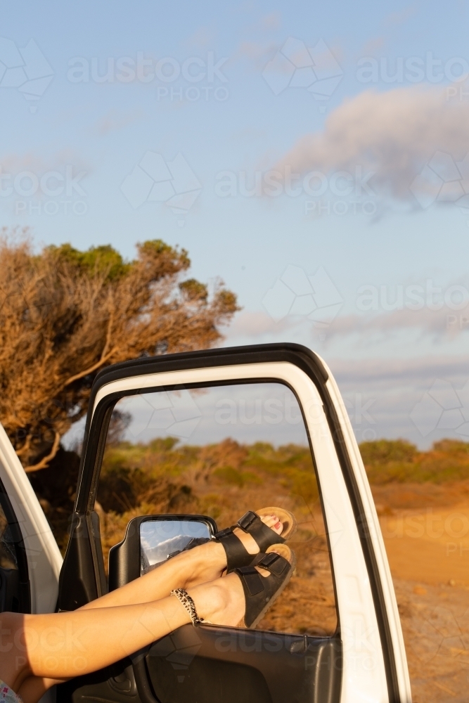 Feet and legs protruding from car door - Australian Stock Image