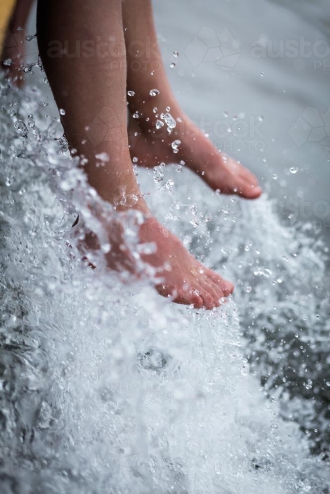 Feet hanging in white water on the boat - Australian Stock Image