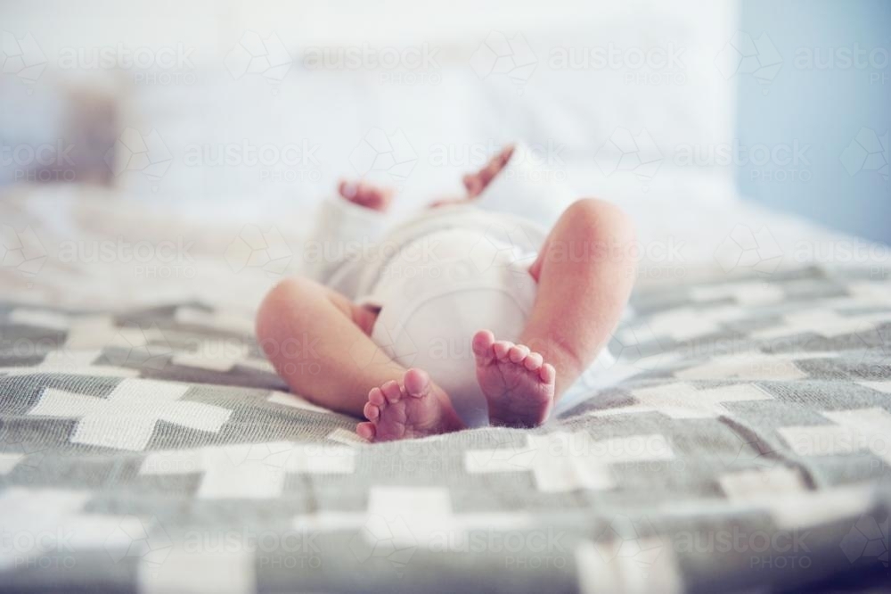 Feet of baby laying on bed - Australian Stock Image